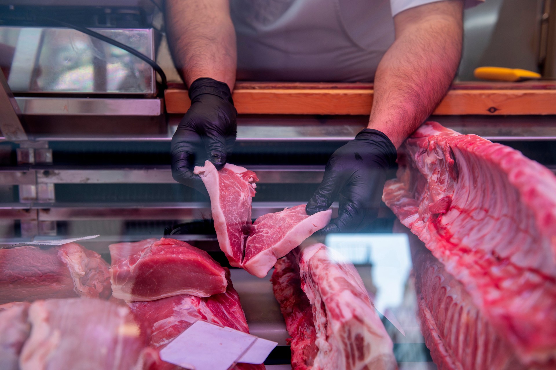 Butcher arranging fresh pork cuts in display case