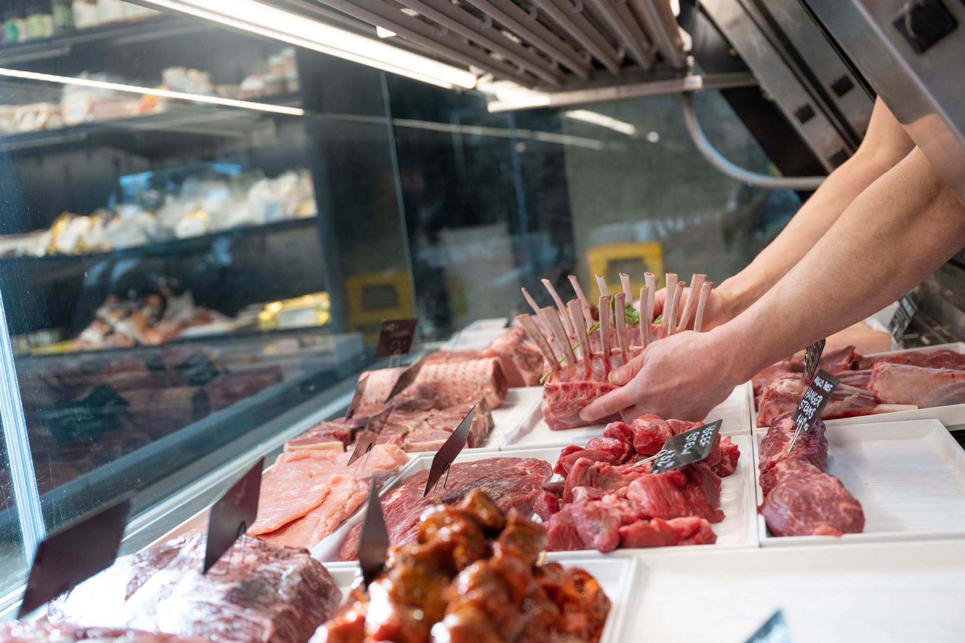Butcher puts meat in display case